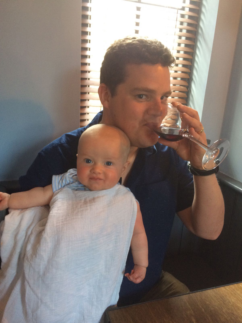man drinking wine with baby