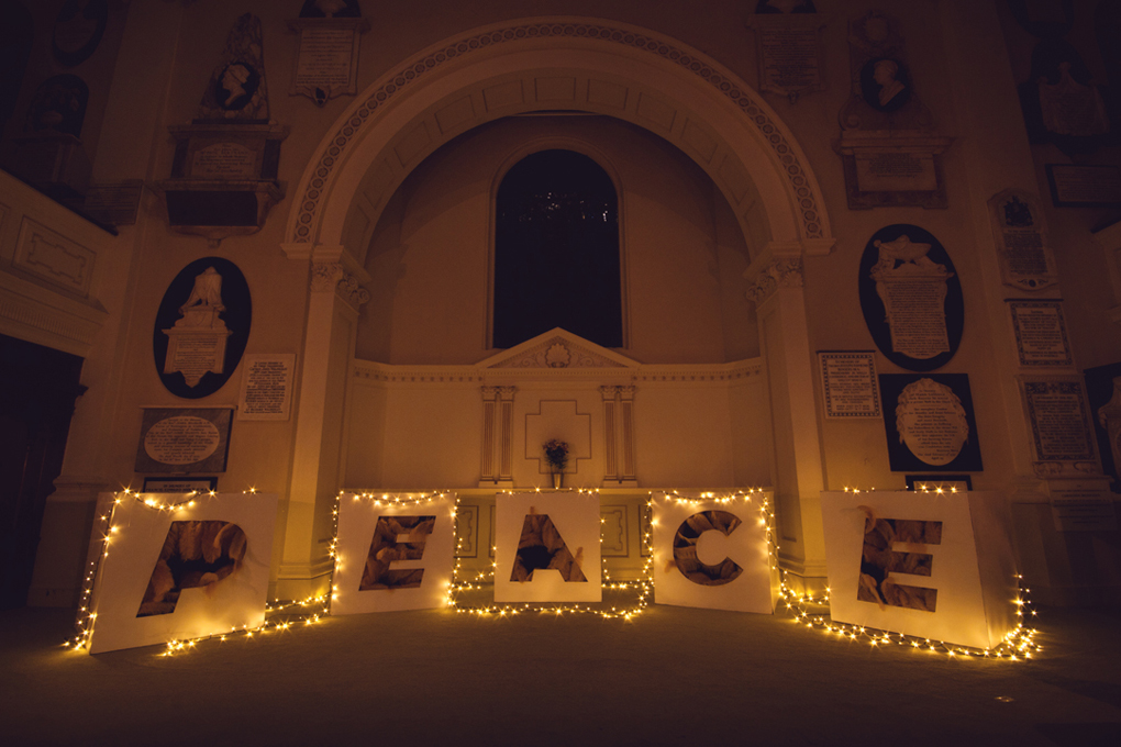 Art installation of golden feathers spelling out the word 'Peace' in St Swithin's Church in Bath.