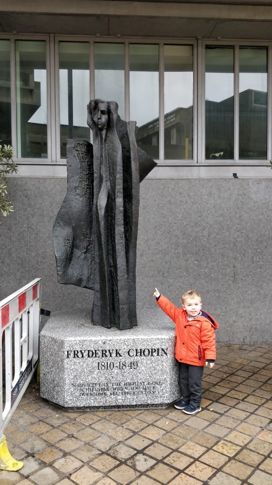 small boy pointing at statue of Chopin