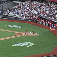 A view of a baseball match from the stands. The stadium is big and relatively full.
