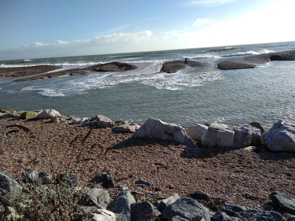 This picture shows the waves crashing over the shingle wall of a lagoon