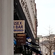 Part of a shop sign with the left side obscured to reveal the apparent sign 'Sex Bar'.
