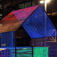 A set of geometric shapes and structures covered in colourful, flourescent wires.