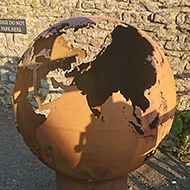 A rusty old globe of metal approx 3 1/2ft in diameter, set on a smaller cylindrical tube of the same. The map of the world had been cleverly cut out in the surface of the globe, the rust illuminated in the sunlight. Cool concept for a sculpture!