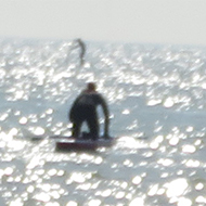We see sunlight dance on the sea at Goring on Sea with a paddleboarder in the distance