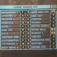 The day's football results, illustrated on a re-usable board where team-names are stuck-on and scores are illustrated thanks to pieces of tape with the numbers 1-9 on them and threaded through the board. A photograph in the corner of the image shows how the pieces of tape and are pulled through to display the correct score on-screen.