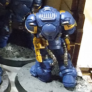Space marine models sit on a wall overlooking an enemy army.