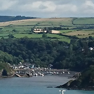 A view of Fishguard harbour with its lovely little town and small horse-shoe shaped marina on one of the few sunny days in August, under a rare blue sky with a bank of cumulus clouds along the horizon. A great view point at the top of a cliff on the opposite side of the harbour in Goodwick.