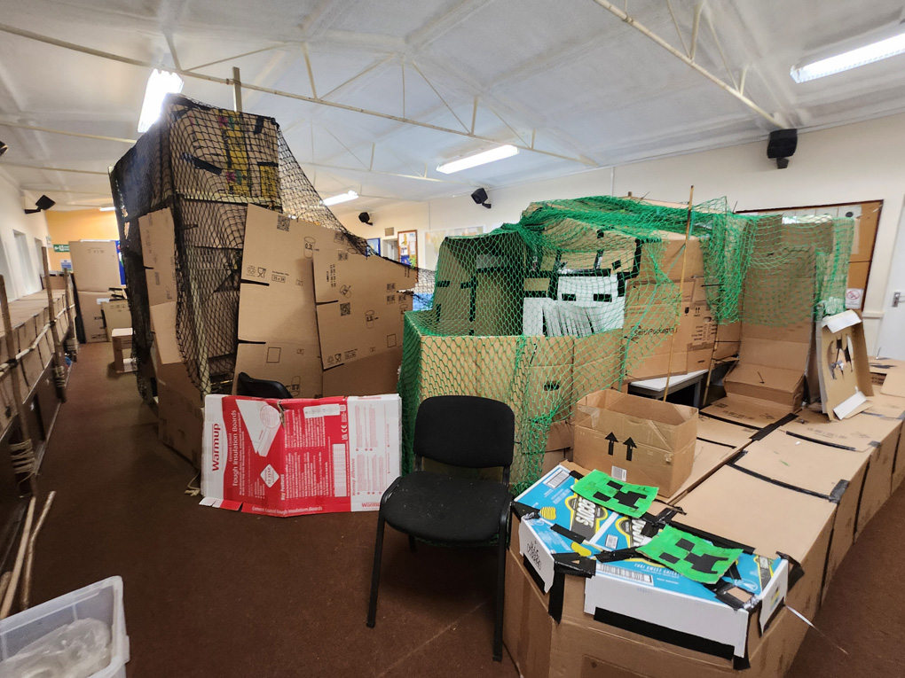 Boxes and boxes of cardboard lie across the floor and tables to form a fully enclosed caving system