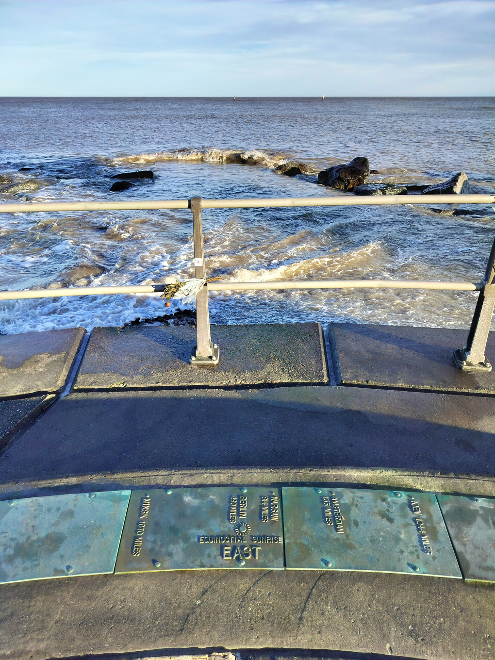 A view of the sea. On the floor a plaque and arrow pointing towards equatorial east.