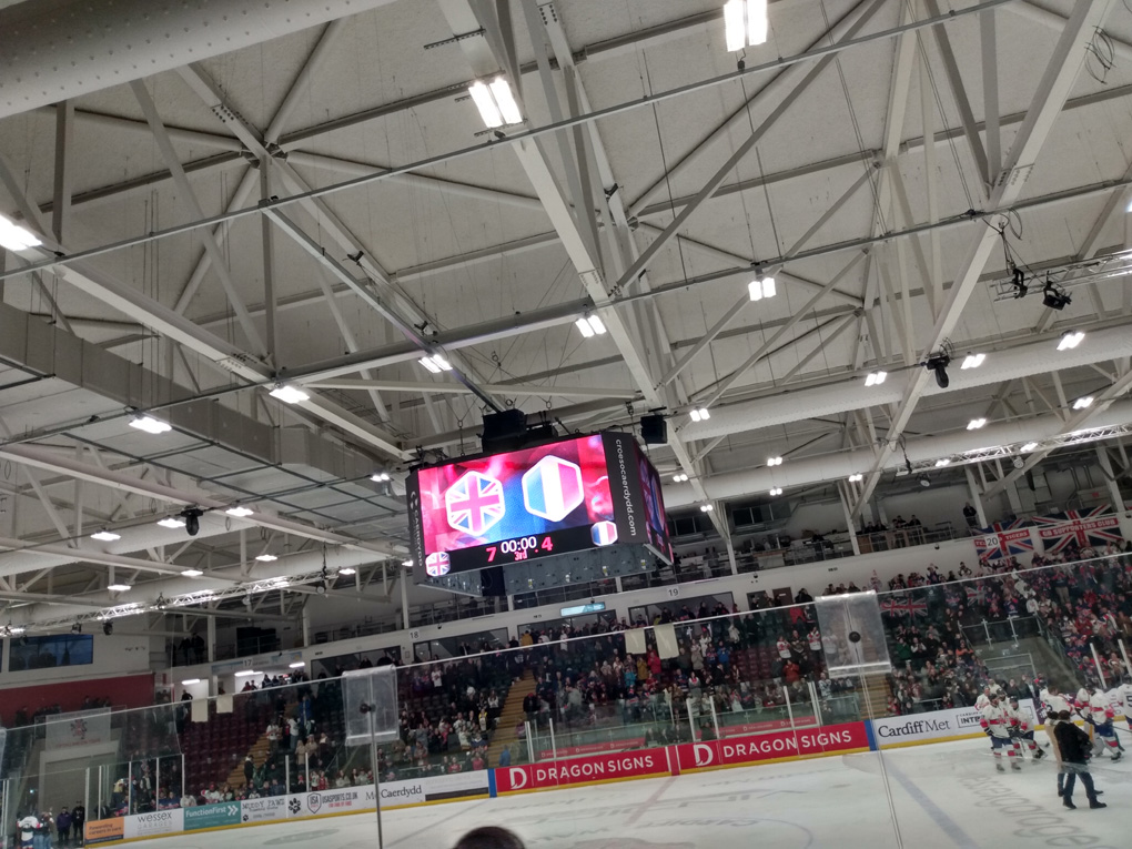 A scoreboard hangs above an ice rink stating GB 7- Romania 4