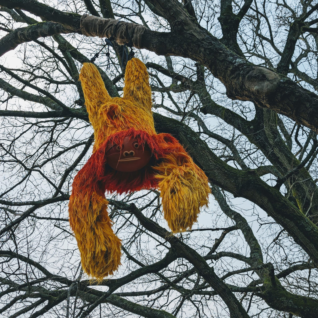 Colourful model sloth hanging from a tree