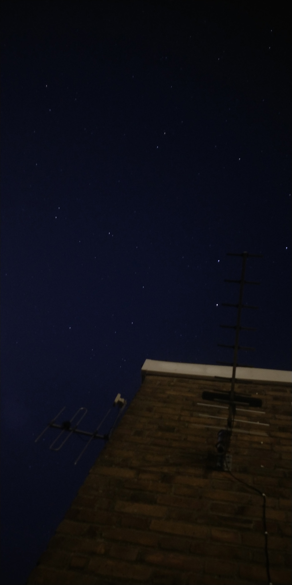 Abstract photo of sky, aerials, wall, with a few stars from Ursa Major in the middle.