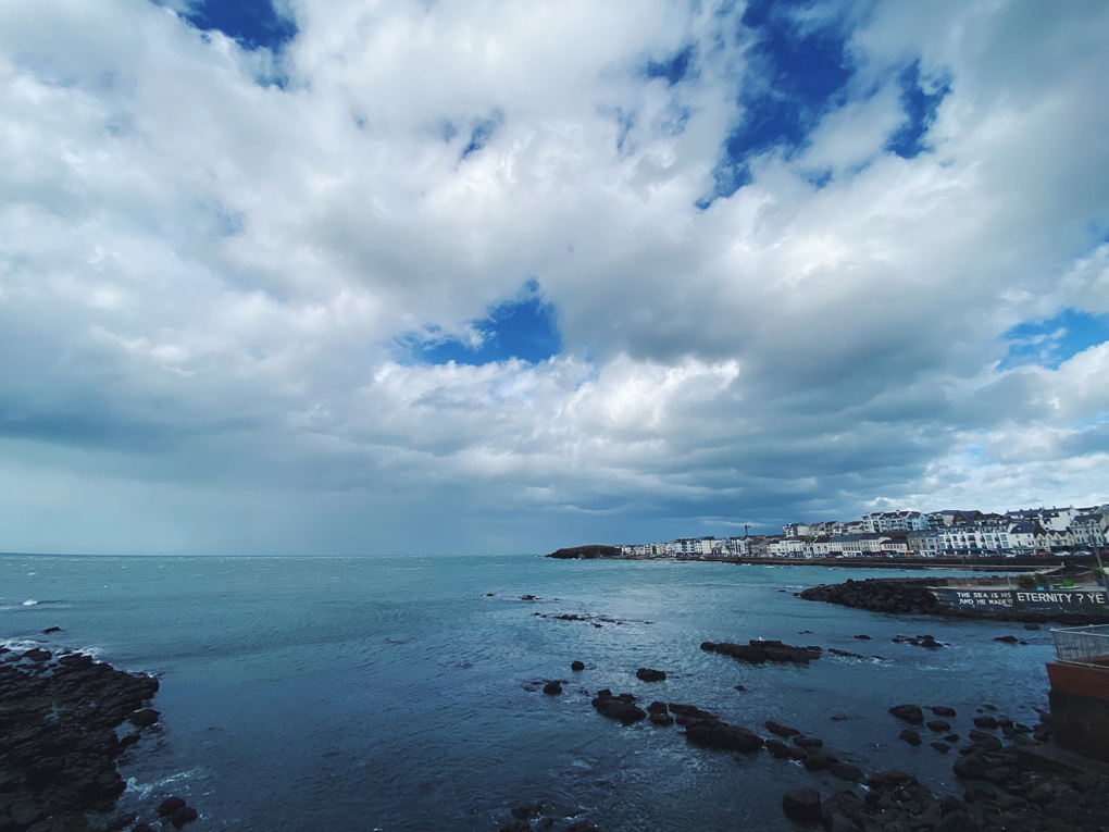 Overlooking the rocky shoreline below the promenade in Portstewart with a huge cloudy sky above.