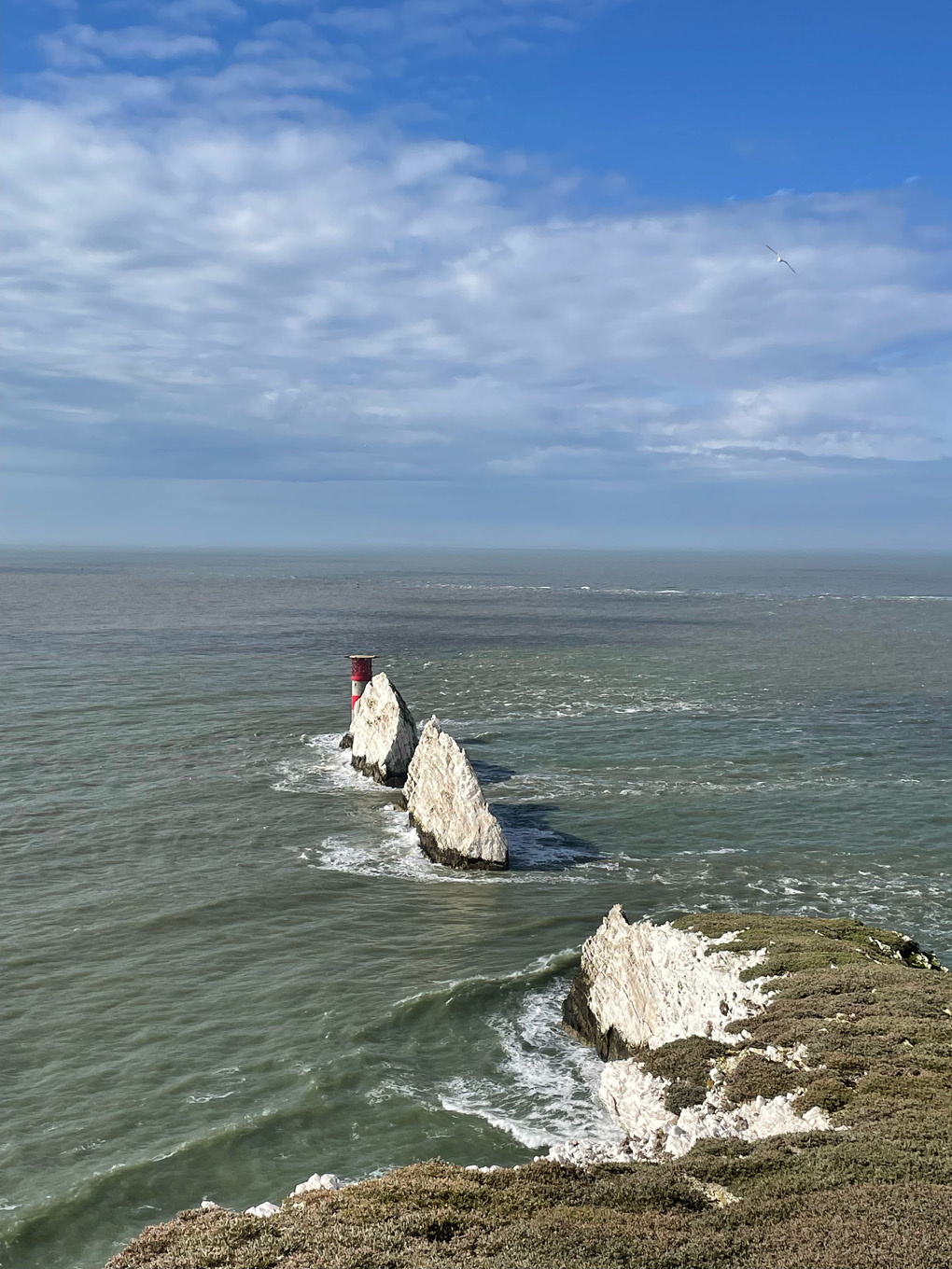 The sea and a chalk cliff outcrop with a lighthouse at the end