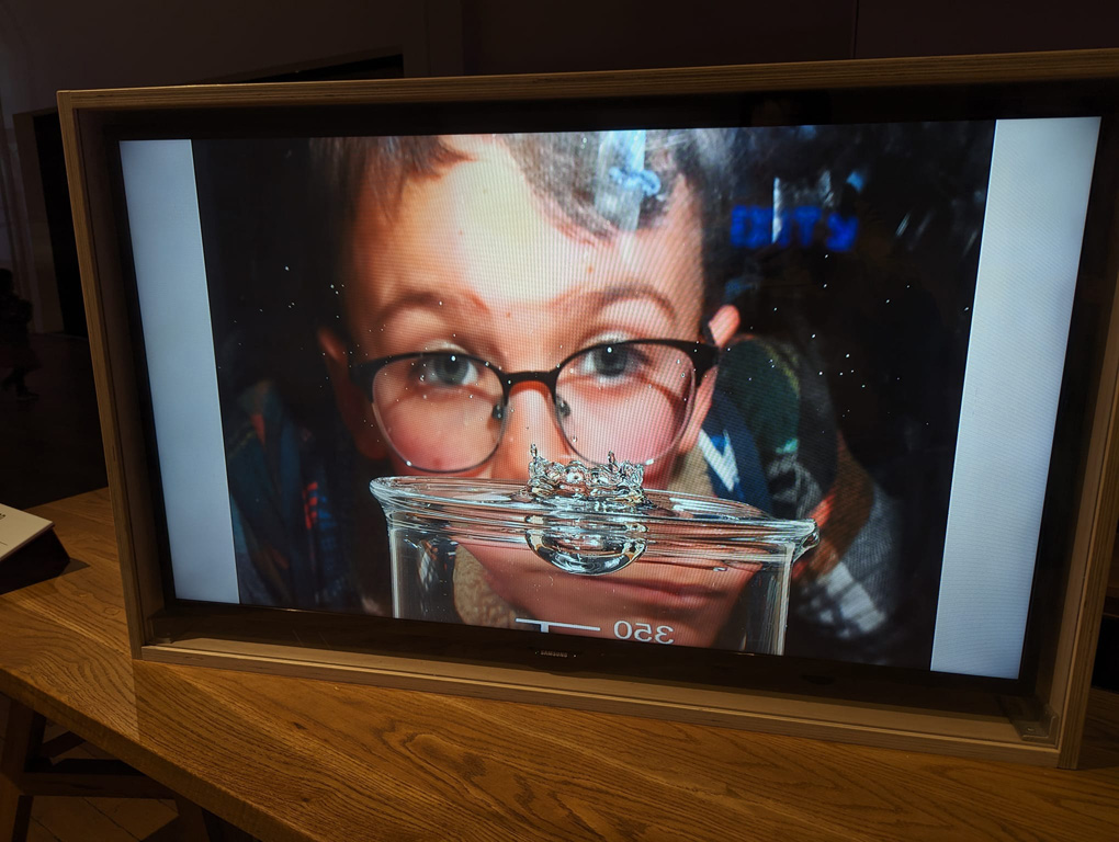 Drop of water falling into a glass of water in front of a bespectacled man