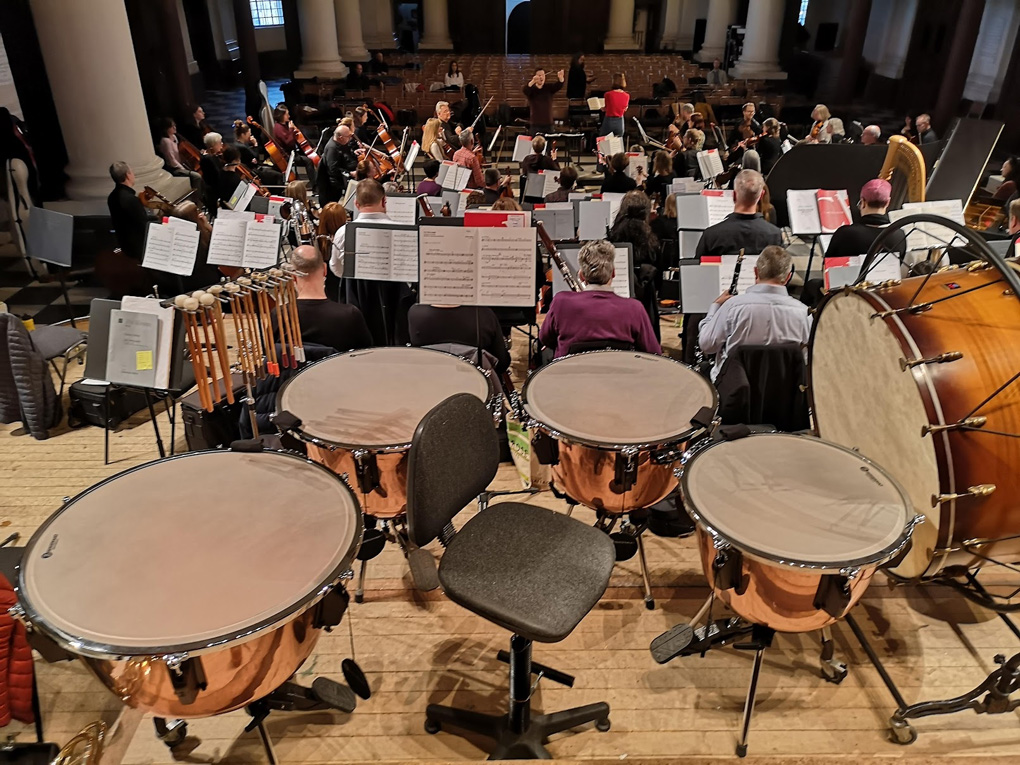 Four timpani and the orchestra rehearsing.