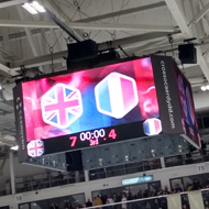 A scoreboard hangs above an ice rink stating GB 7- Romania 4