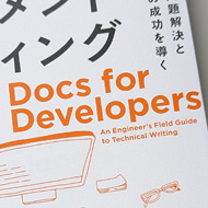 A book on a desk. The front cover is covered in Japanese text with the only words in English: Docs for Developers
