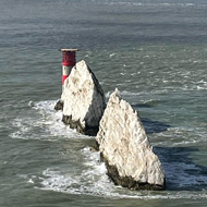 The sea and a chalk cliff outcrop with a lighthouse at the end