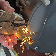 Man standing at a grinder with sparks flying
