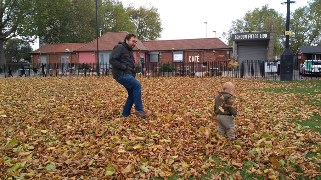 man and toddler playing in fallen leaves