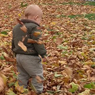 man and toddler playing in fallen leaves