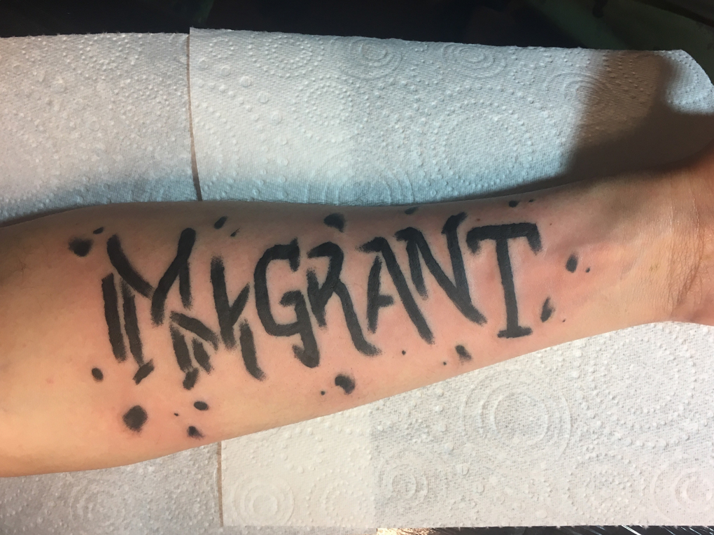 The inside of Sean's left forearm with a fresh tattoo that reads 'immigrant'