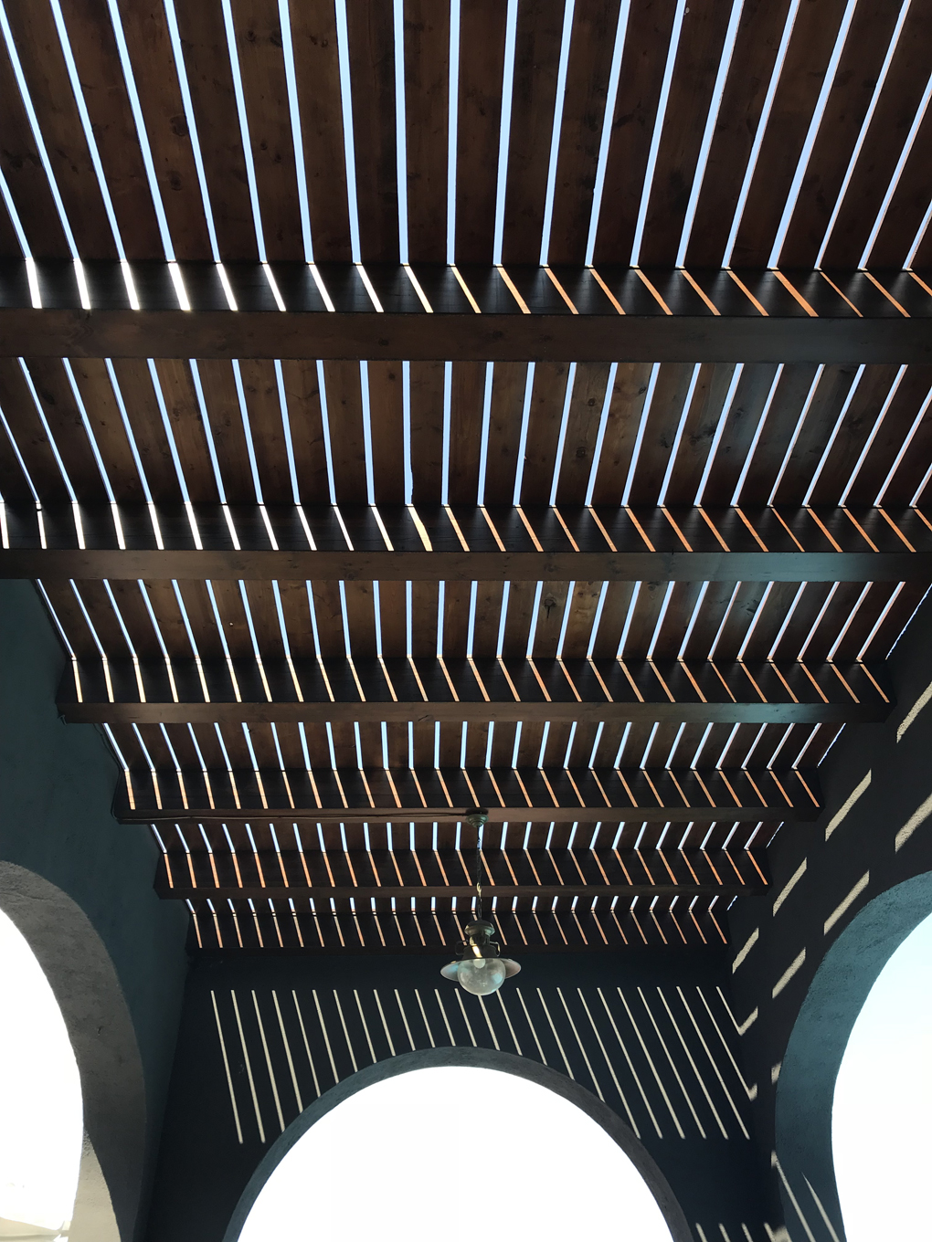 A geometric pattern created as sun shines through wooden slats
