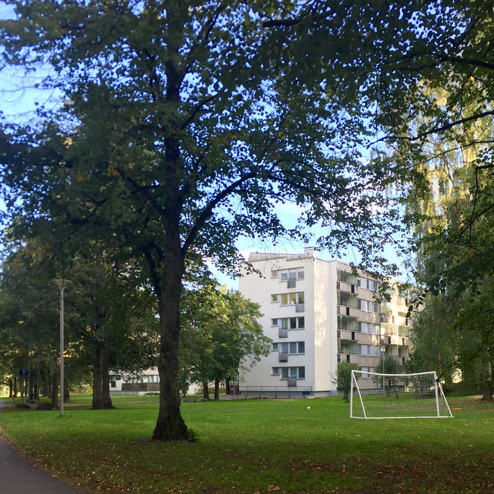 An appartment building, trees and a football goal.