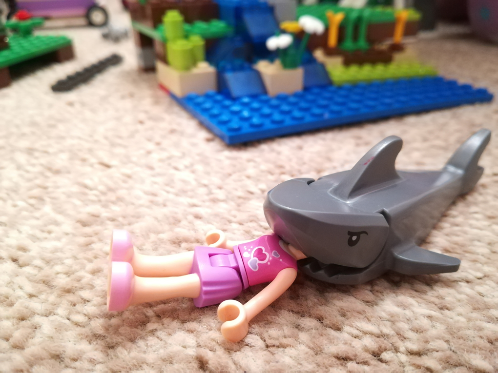 A shark is devouring a lego minifigure, headfirst
