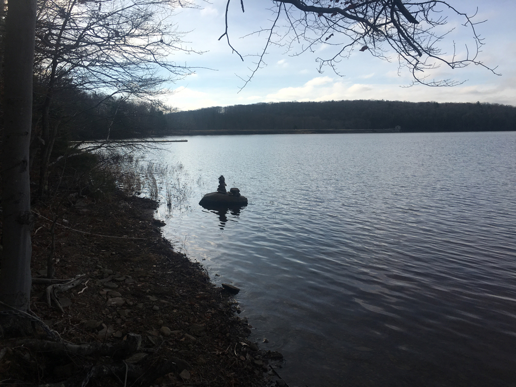 Rocks carefully piled to create a tower on the shore of a quiet lake