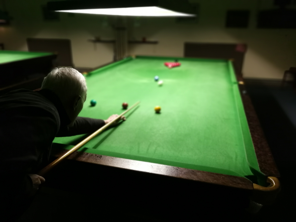 man playing snooker shot over his shoulder