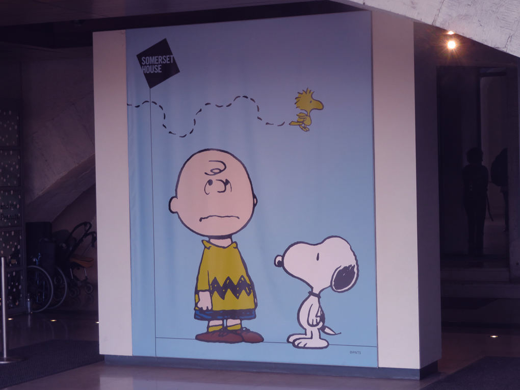 The picture is of a large poster featuring Charlie Brown, Snoopy and Woody from the Peanuts cartoon outside the exhibition entrance at Somerset House