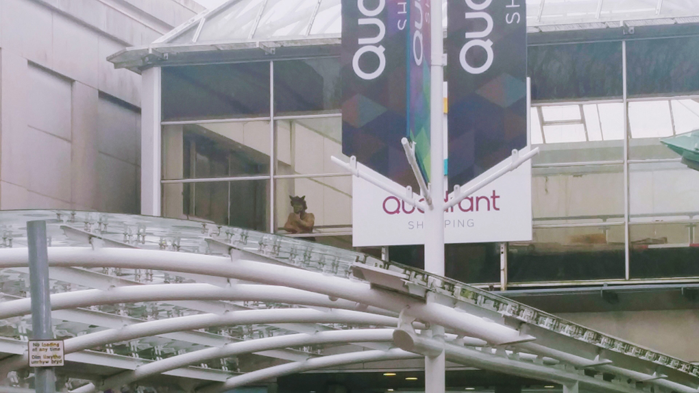 A small statue of a devil peering out of the upstairs window of the Quadrant Shopping Centre in Swansea.