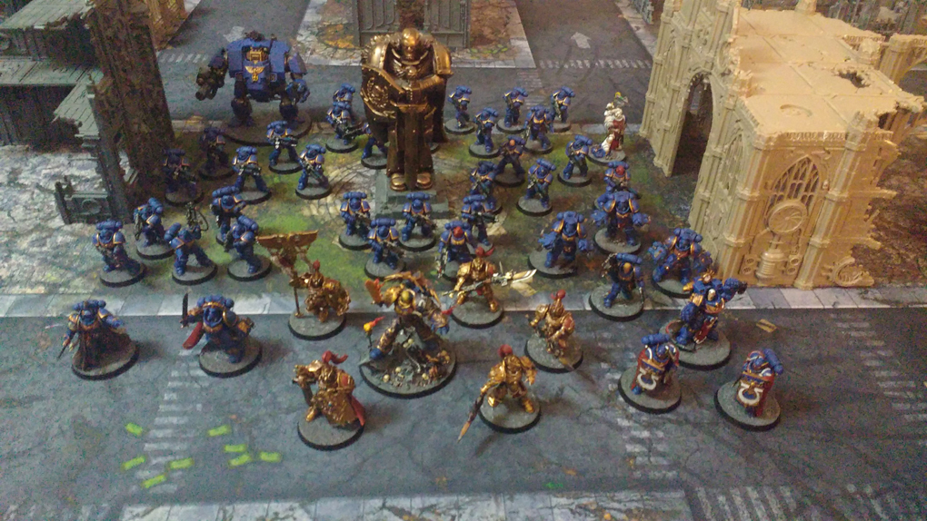 Blue 28mm tall plastic space marines arrayed on a printed city mat