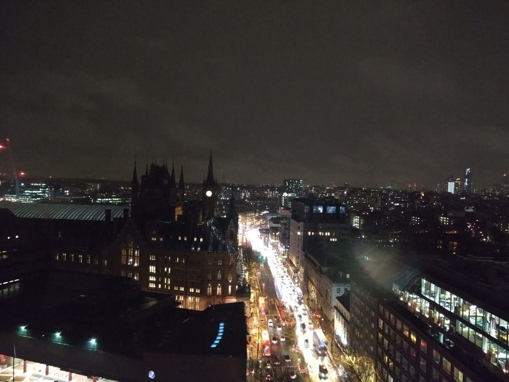 london at night from a high point, river of light along a road