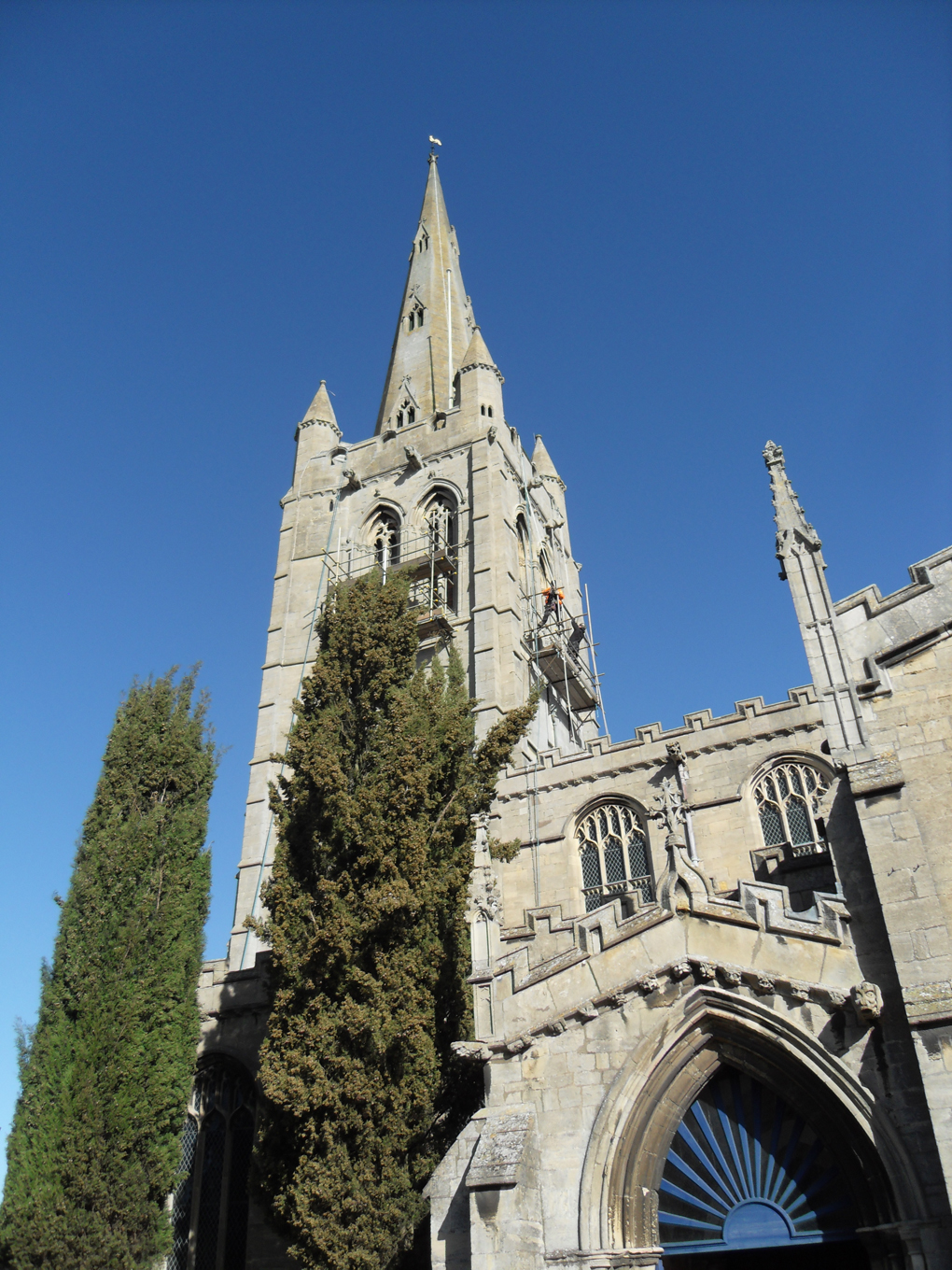 Workmen on scaffolding high up church tower