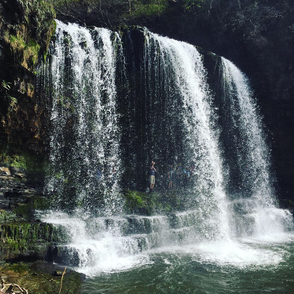 A large waterfall, with people standing behind it