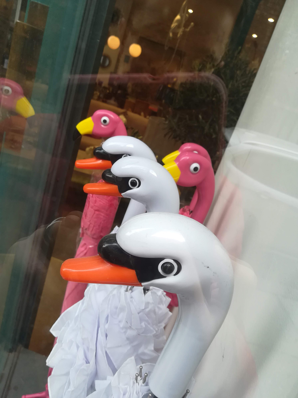 The handles of several umbrellas, shaped like swans and flamingos.