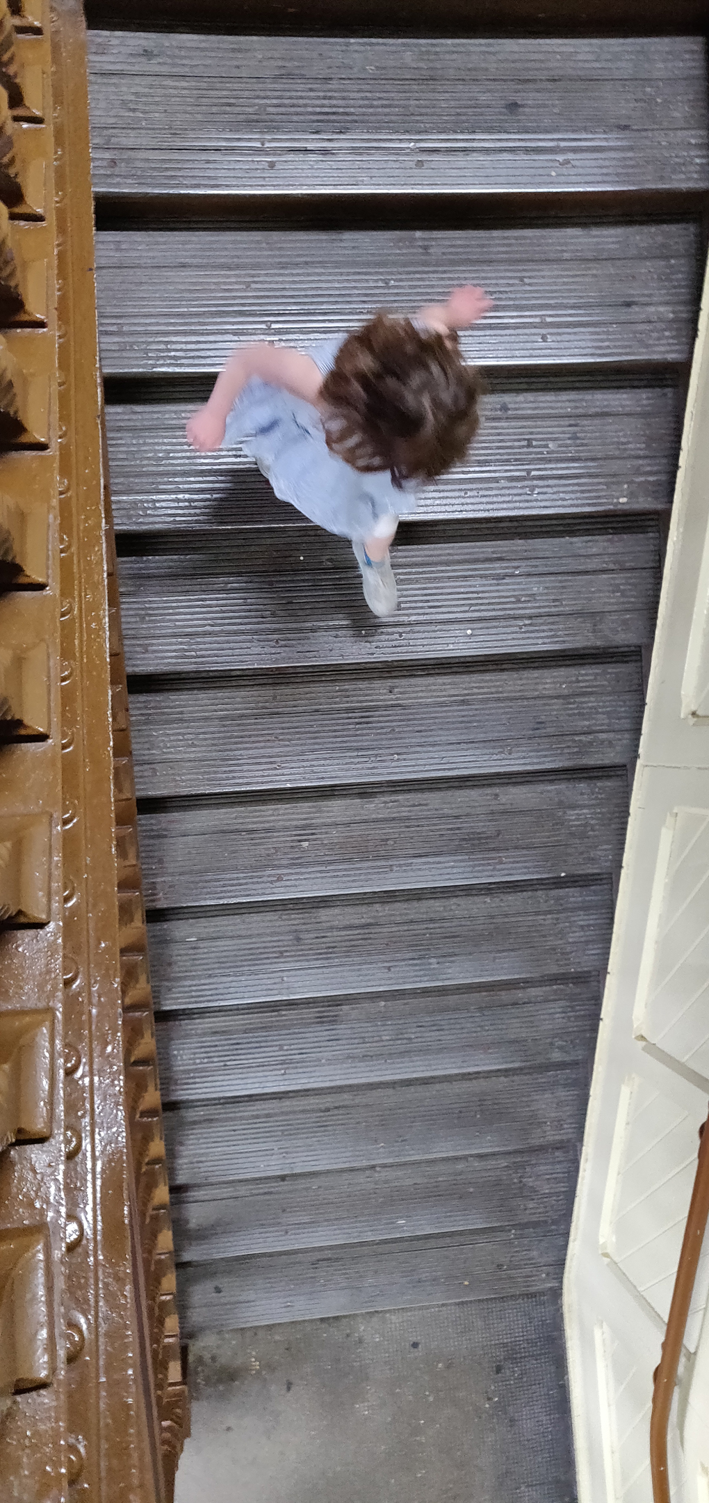 A child running down an old wooden flight of stairs shot from above