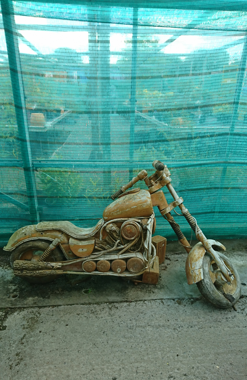 A crazy and brilliantly made Easy Rider motorbike with extended forks, parked in a quirky garden centre, looking a bit worse for wear, needing a bit of a refurb - all cleverly made of wood but not for sale!