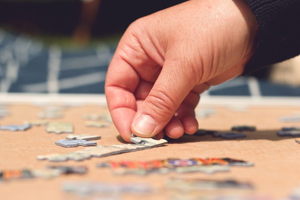 Hand placing puzzle pieces.