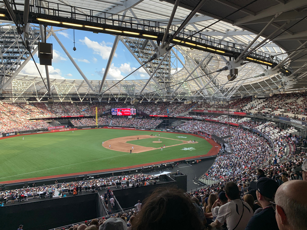 A view of a baseball match from the stands. The stadium is big and relatively full.