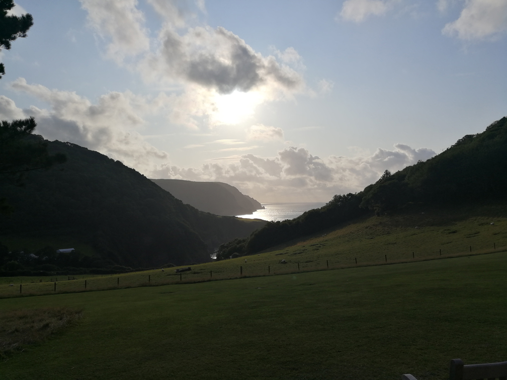 view of the sea between hills with the sun going down