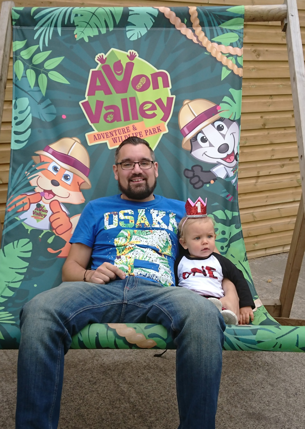 A ginormous deckchair at the entrance to Avon Valley Wildlife Park in which two cheeky chaps are sitting - my youngest son Lawrence and his son Jaxson who is wearing a little red crown with number 1 on.  We spent a fun day there for Jaxson’s first birthday. The prize attraction was The Pig Race run by five year old Saddle Back pigs. We fell in love with Barry an Aragolis goat. He had two large curved horns and long ears and stood 4 1/2 feet tall! A gentle giant.