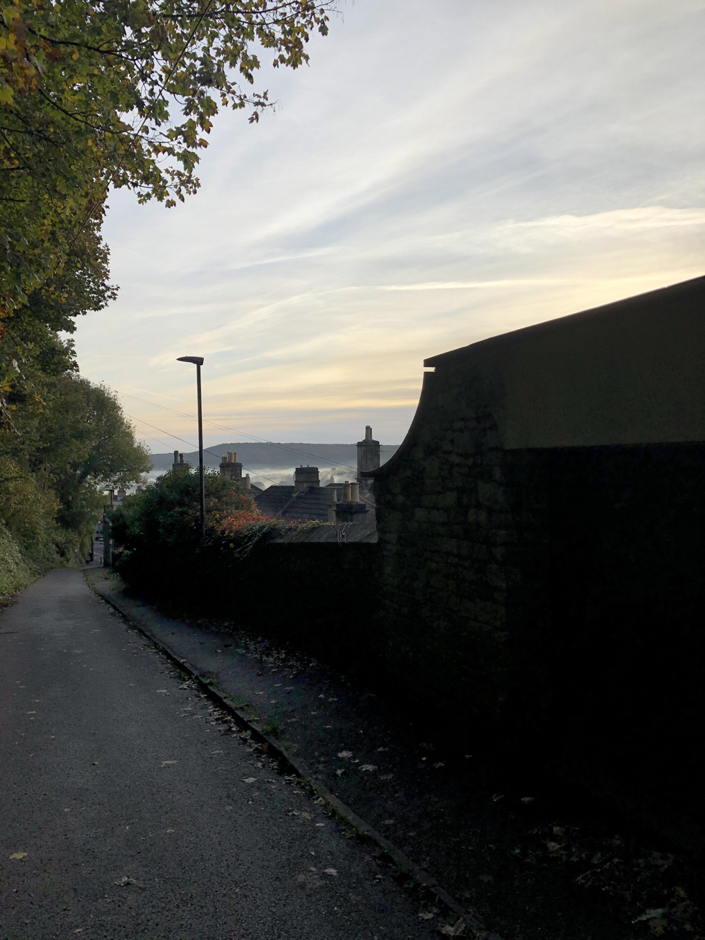 A view down a winding road. In the background is a multi-coloured pastel sky.