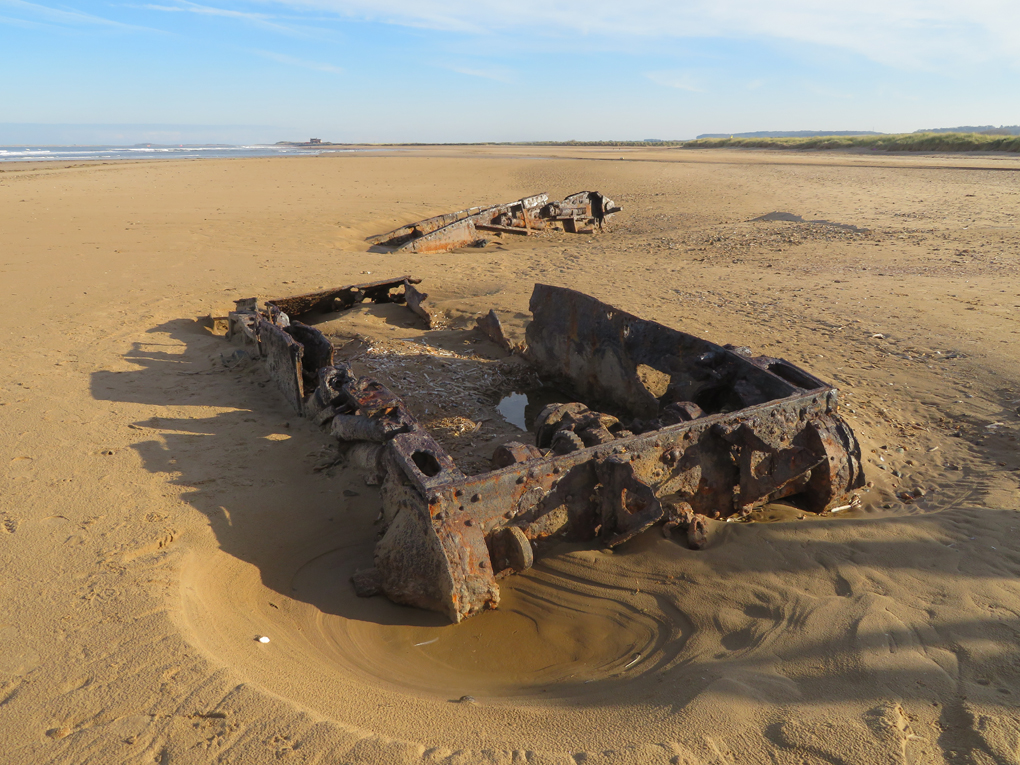 we see the rusting hulls of two WW2 Covenanter tanks half buried in the sand on the beach at Titchwell North Norfolk, with the sand in the background