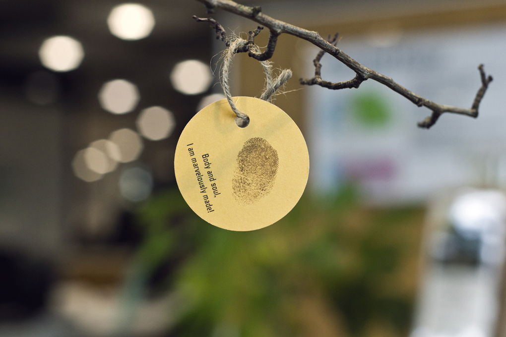 Close up of a paper leaf, with a thumbprint and a quote reading, 