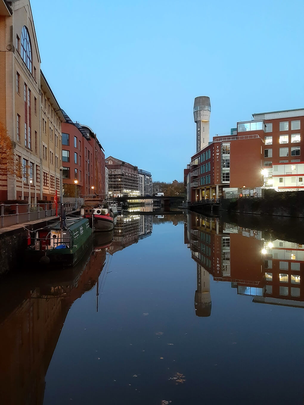 Looking along a very still river in the middle of a busy city in late sunrise light